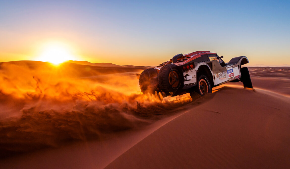 Red rally car drifting on sand dunes at sunset – desert rally photography by Zypix Dubai